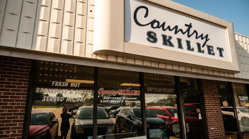 Country Skillet restaurant exterior with prominent sign, brick facade, and reflections of parked cars.